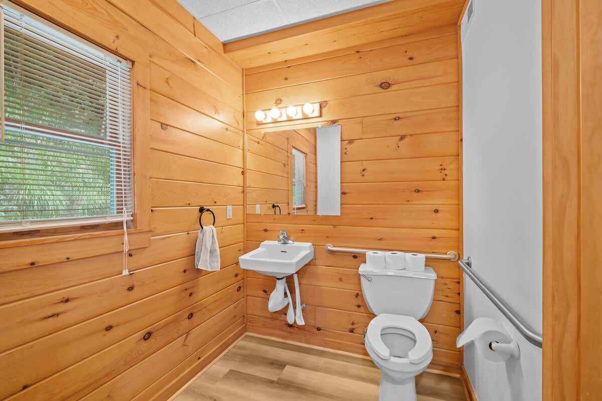 Ein Badezimmer mit Holzpaneelen, Waschbecken, Toilette und Spiegel.
