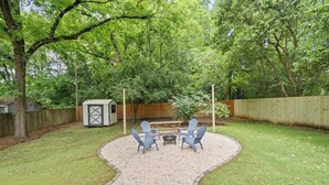 A backyard with a fire pit, two chairs, and a small shed. - West End Hideaway - Enderly Park - Fruit Trees (Charlotte)
