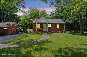 A two-story brick house with a front porch, a driveway, and a well-maintained lawn. - West End Hideaway - Enderly Park - Fruit Trees (Charlotte)