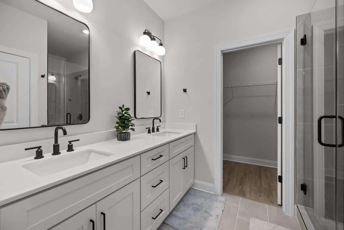 Un baño con un espejo grande, dos lavamanos, ducha y vestidor.
