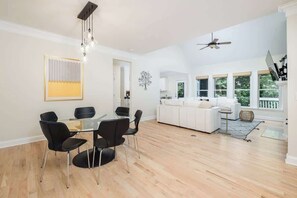 Un'ampia zona giorno con tavolo da pranzo, sedie, divano e ventola a soffitto.