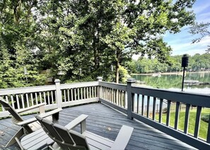 A wooden deck with chairs, a railing, and a view of a lake. - Blissful Lake Views + Hot Tub + Pool Table (Huntersville)
