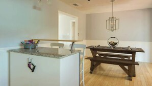 A kitchen with a granite countertop, a wooden dining table, and pendant lighting.