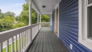 A covered porch with a railing, a window, and a view of greenery. - Family/Pet Friendly - Professional Design (Concord)