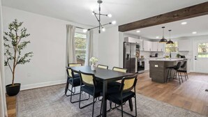A modern kitchen with a central island, a dining area with a table and chairs, and a potted plant. - Family/Pet Friendly - Professional Design (Concord)