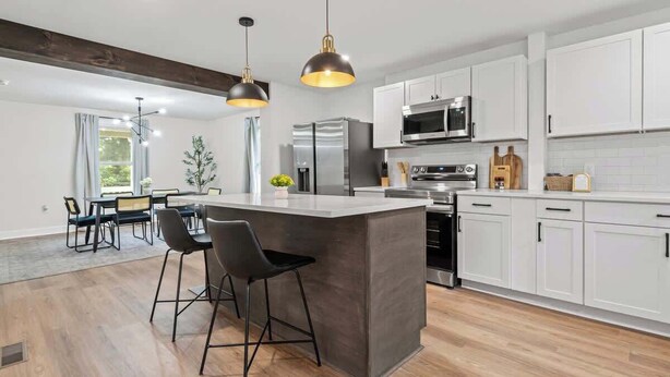 A modern kitchen with white cabinets, stainless steel appliances, and a central island with bar stools. - Family/Pet Friendly - Professional Design (Concord)