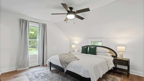 A bedroom with a bed, a ceiling fan, two bedside lamps, a window with curtains, and a patterned rug. - Family/Pet Friendly - Professional Design (Concord)
