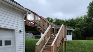 Ein Wohnhaus mit einer Holztreppe, die zu einer Terrasse, einer Garage und einem Rasen führt.