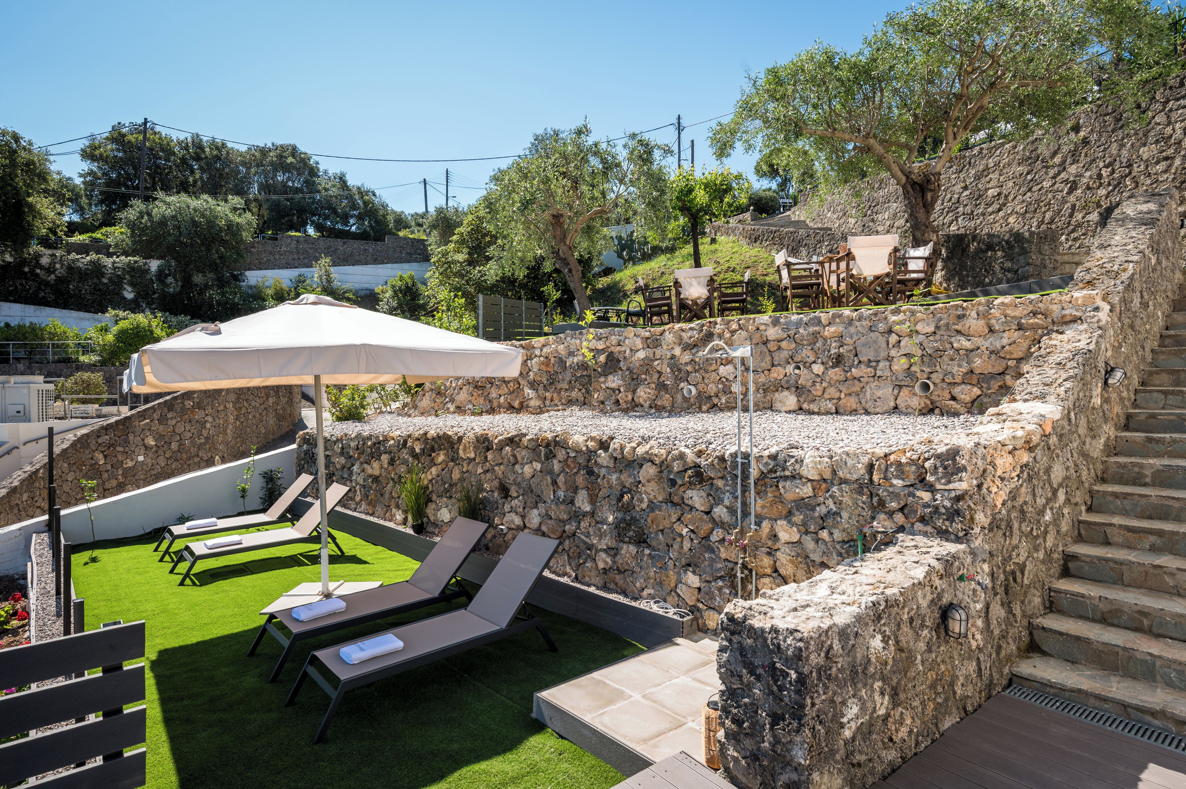 A stone wall with a small garden area, outdoor seating, and a staircase.
