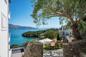 A terrace with a table and chairs, overlooking a lake and mountains. - Apovrado Stay, Kommeno (Corfu)