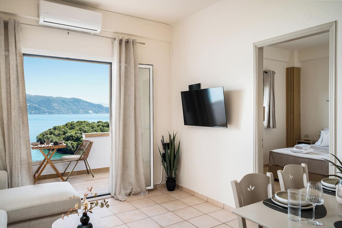 Ein Hotelzimmer mit Balkon, Fernseher, Essbereich und Bett.