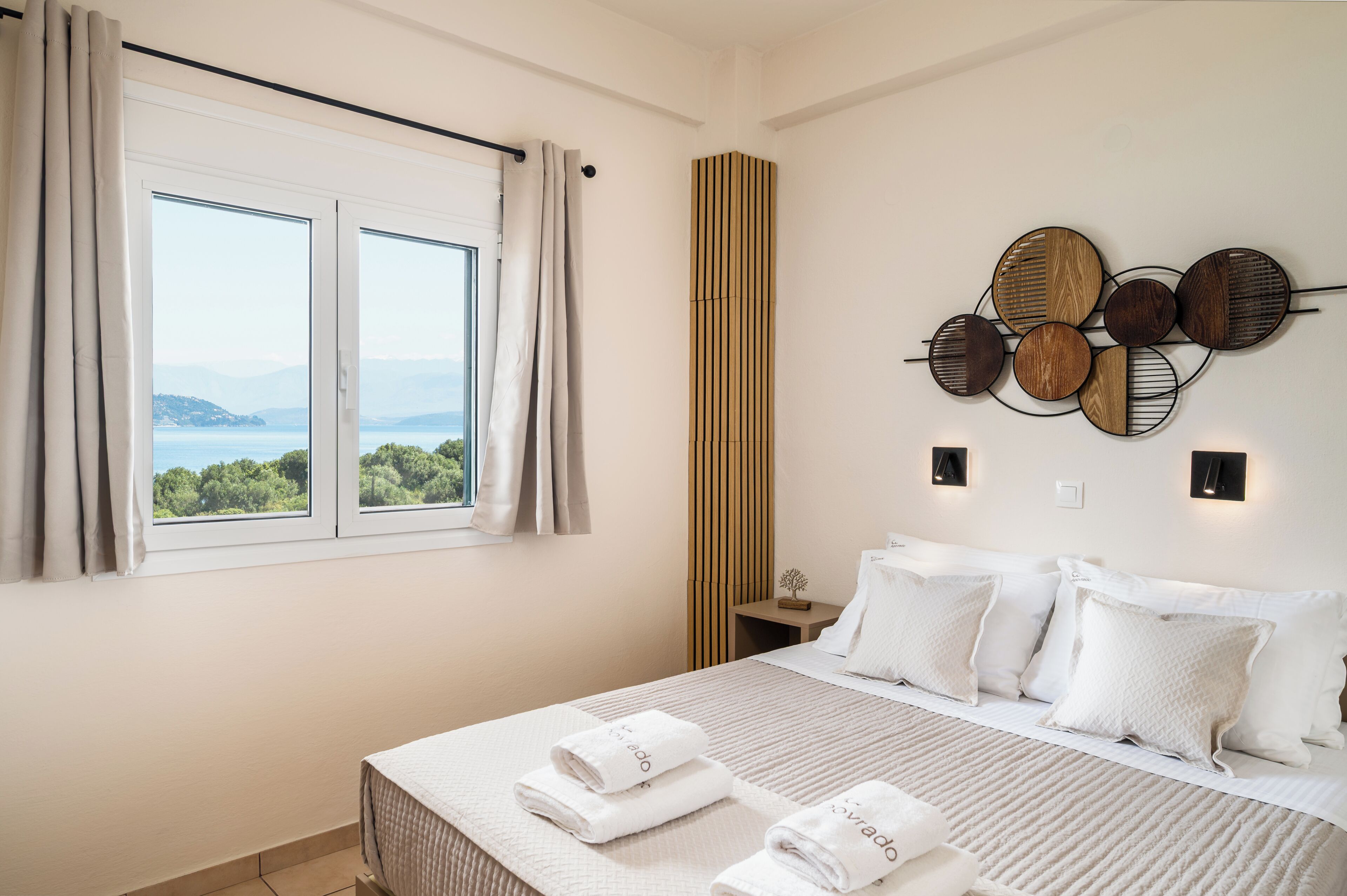 A bedroom with a bed, pillows, a wall-mounted light fixture, and a window with curtains.