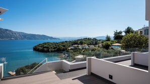 A modern building with a glass balcony overlooking a lake, surrounded by greenery and distant mountains. - Apovrado Stay by Konnect, Kommeno (Corfu)