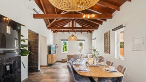 Un comedor con mesa de madera, sillas y una lámpara colgante.