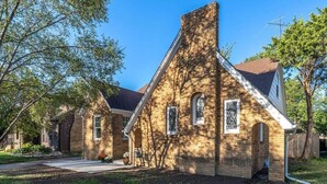 A brick house with a chimney, a front porch, and a small garden. - Captivating Rose Cottage-3 King Beds-College Hill (Wichita)