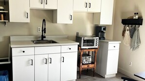 A compact kitchen with white cabinets, a built-in toaster oven, and a coffee maker on the countertop. - Home away from home in quiet village near Lake Erie. (Selkirk)