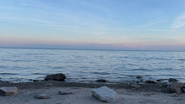 A beach with calm water, scattered rocks, and a clear sky. - Home away from home in quiet village near Lake Erie. (Selkirk)