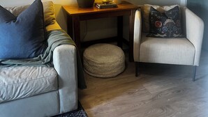 A living room with a sofa, a chair, a small table with a lamp, a vase with branches, and a rug. - Home away from home in quiet village near Lake Erie. (Selkirk)