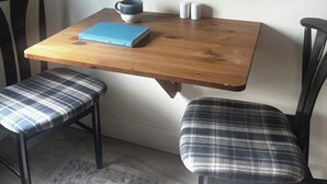 A dining table with a book, a mug, and salt shakers. Two chairs with plaid cushions are positioned at the table. - Home away from home in quiet village near Lake Erie. (Selkirk)