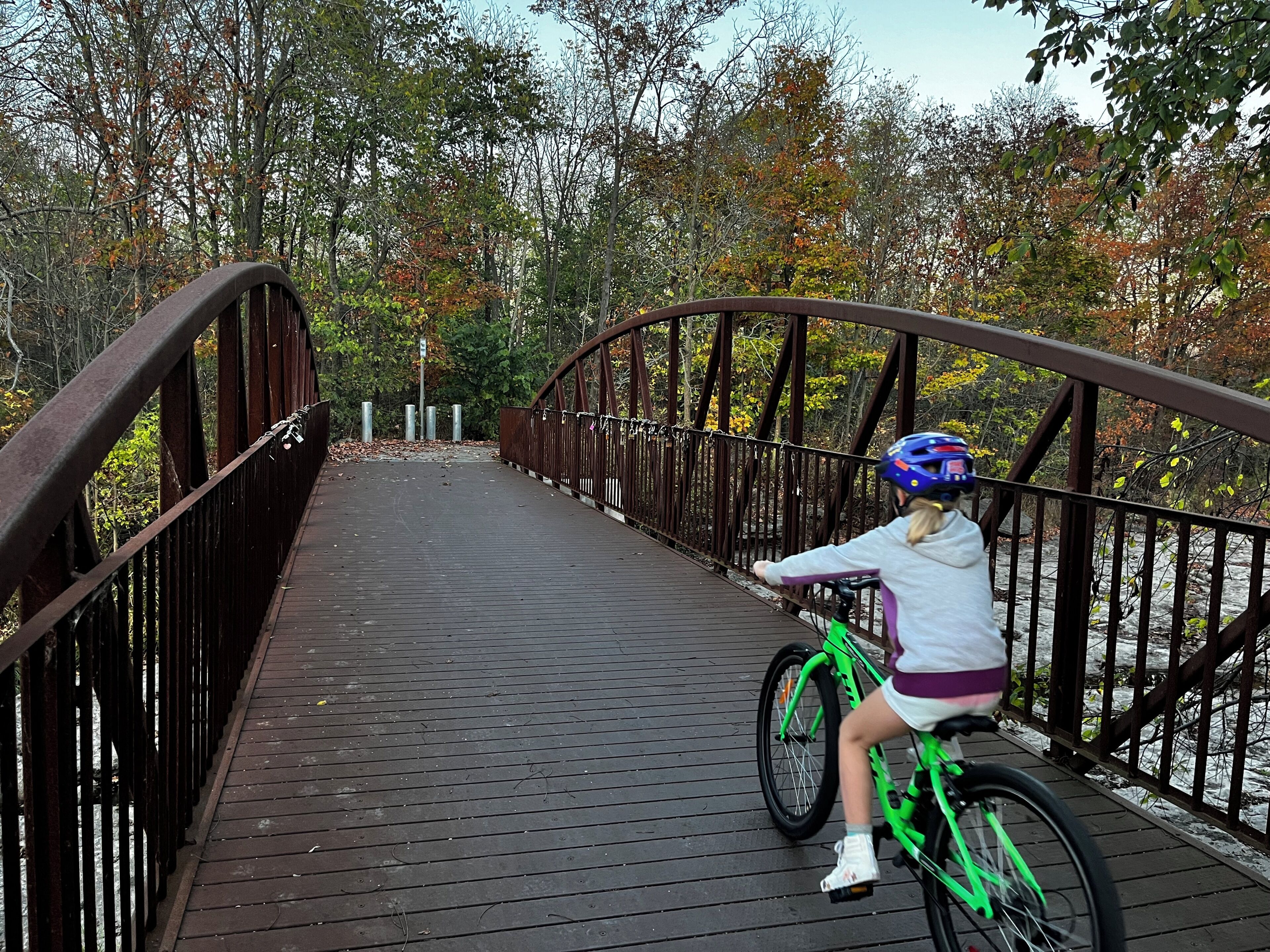 A person riding a bicycle on a wooden bridge with metal railings.