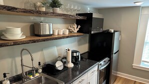 A modern kitchen with a stainless steel sink, black appliances, and white cabinetry. - Cozy 1-bedroom apartment with parking in walkable Portland location (Portland)