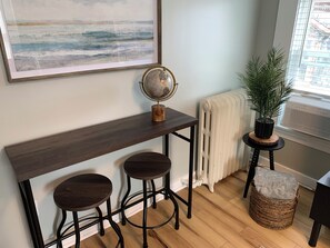 A room with a wooden bench, two stools, a globe, a radiator, a potted plant, and a large abstract painting. - Cozy 1-bedroom apartment with parking in walkable Portland location (Portland)