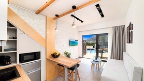 Eine moderne Küche mit Mikrowelle, Kühlschrank und Holzauskładung. Es gibt einen Essbereich mit Tisch und Stühlen sowie einen Balkon mit Blick auf einen Pool.