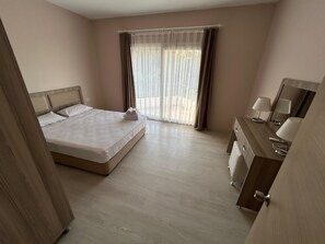 Una camera d'albergo con un letto, una scrivania con una lampada e una finestra con tende.