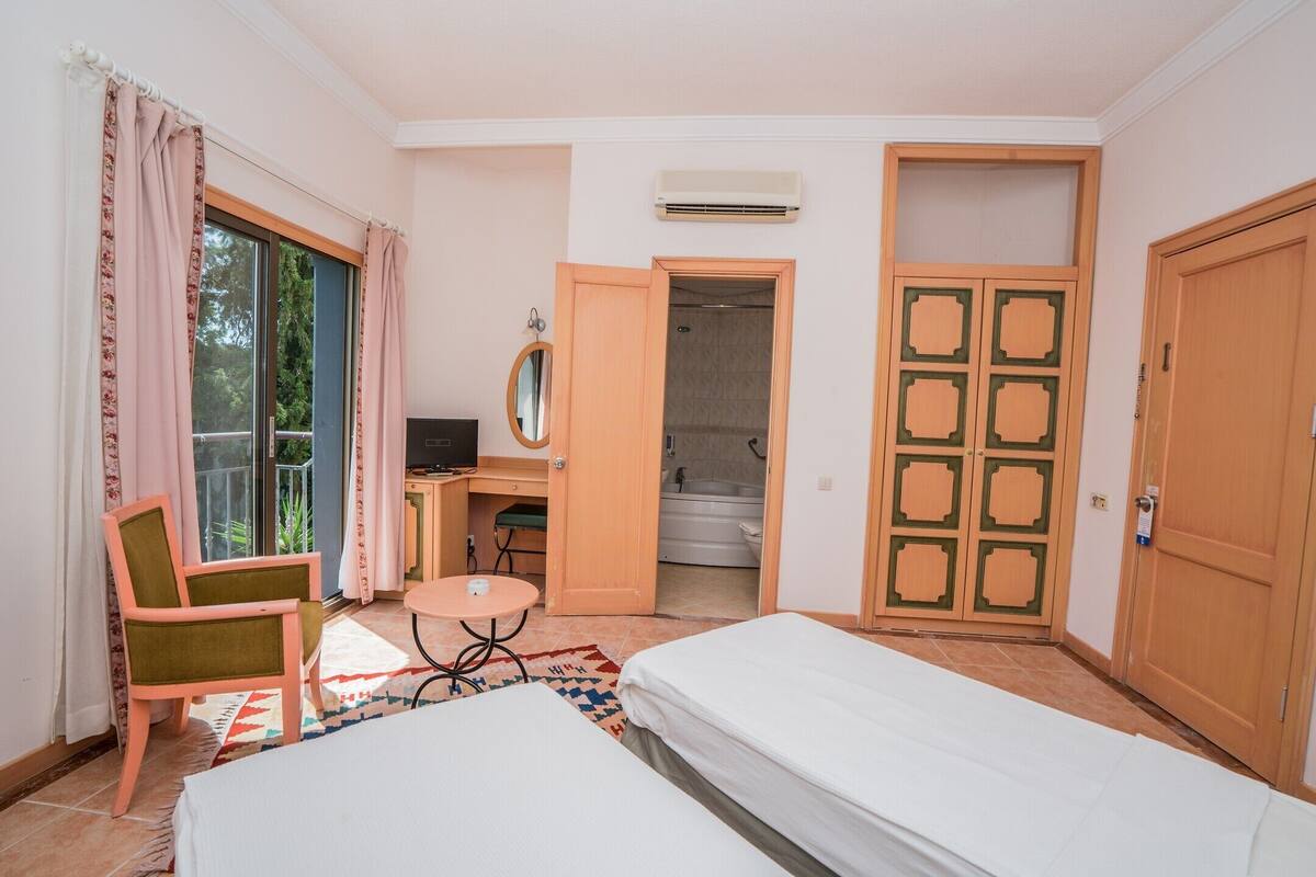 Habitación de hotel con cama, escritorio con silla, baño y puerta con diseño decorativo.