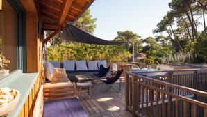A wooden deck with a sofa, chairs, and tables, surrounded by a wooden railing and trees. - La Giovanna - Villa 5bed, heated pool, pine garden, Cap-Ferret (Lège-Cap-Ferret)