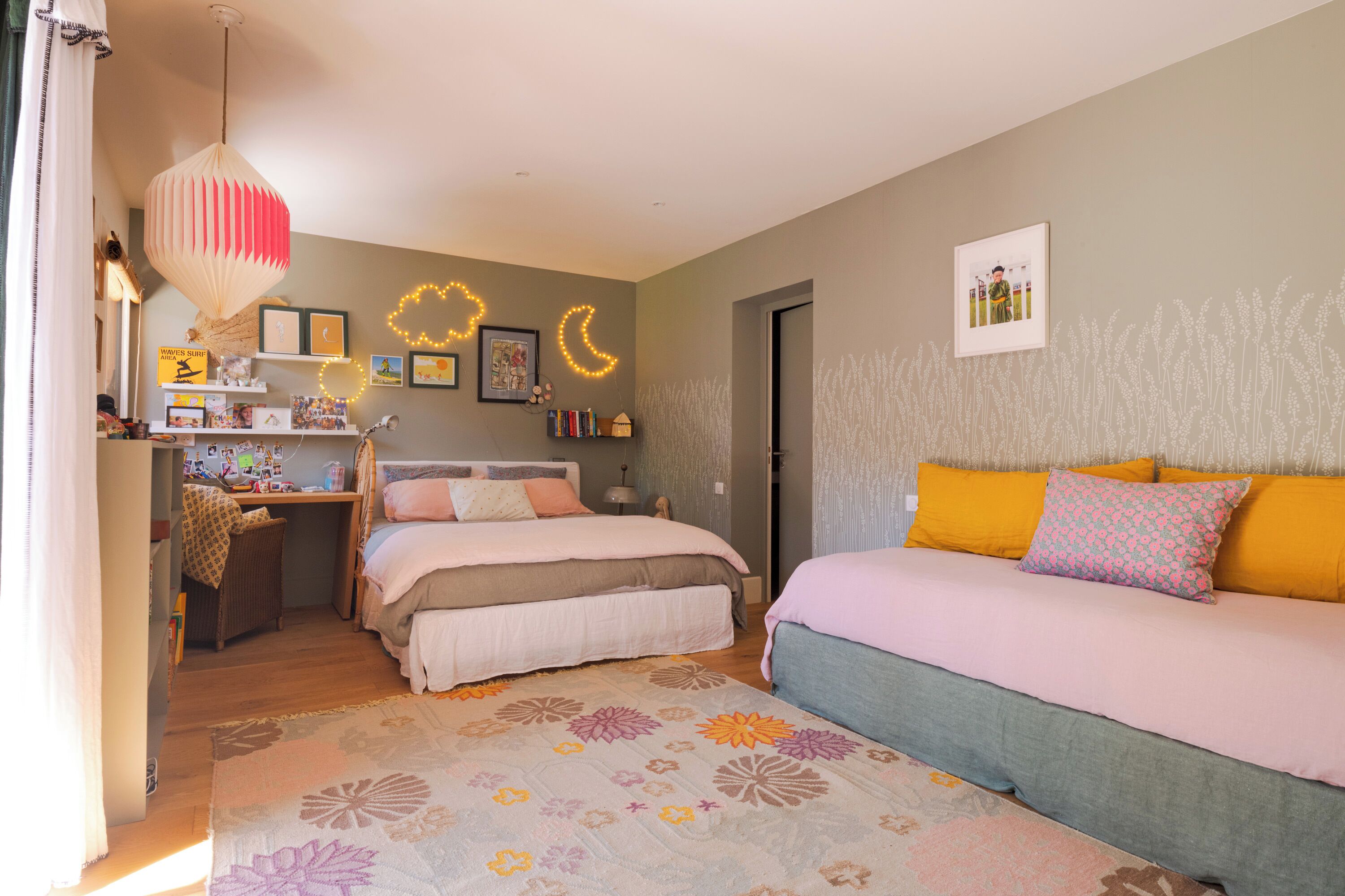 Een slaapkamer met een bed, een bureau en een stoel. Er zijn decoraties aan de muur en een fotolijst.