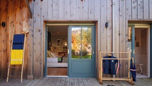 A wooden exterior with a blue door leading to a bedroom with a bed and a view of trees. - La Giovanna - Villa 5bed, heated pool, pine garden, Cap-Ferret (Lège-Cap-Ferret)