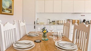 A dining area with a wooden table set for four, white chairs, and a vase with flowers. - The Old Chicken Shed (Stoke Row)