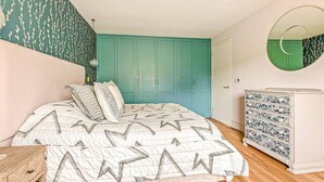 A bedroom with a bed, a dresser, a mirror, and teal-colored walls. - The Old Chicken Shed (Stoke Row)