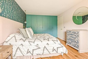 Una camera da letto con un letto, una cassettiera, uno specchio e pareti color acquamarina.