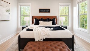 Een slaapkamer met een groot bed, twee nachtkastjes, een bankje en een plafondventilator.