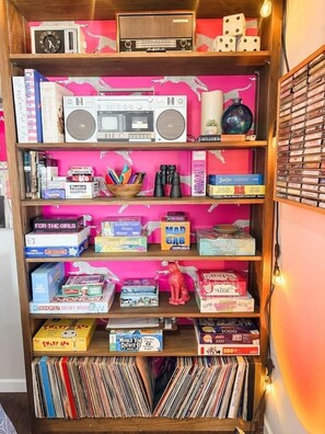 A bookshelf with various board games, a radio, and a globe. - Pink Pearl-Beaver Lake Views-Hot Tub-Sauna (Rogers)