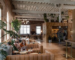 Ein geräumiges Café mit Ledersitzmöglichkeiten, einem Kaffeemarkt und hängenden Pflanzen.
