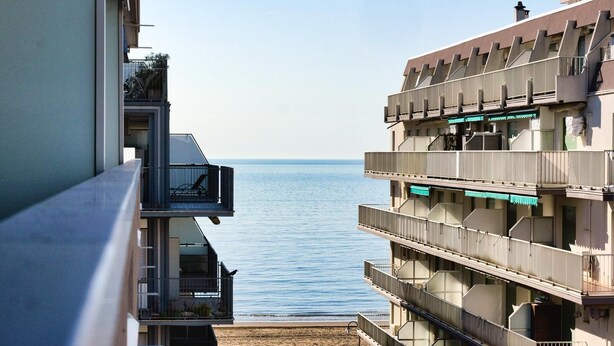 Un edificio de varios pisos con balcones que dan a una masa de agua.
