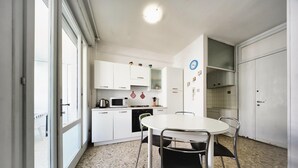 Una cocina compacta con armarios blancos, un microondas y una mesa redonda con sillas.