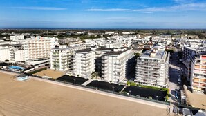 Un complejo residencial de edificios altos con múltiples balcones, una piscina y vistas a la costa.