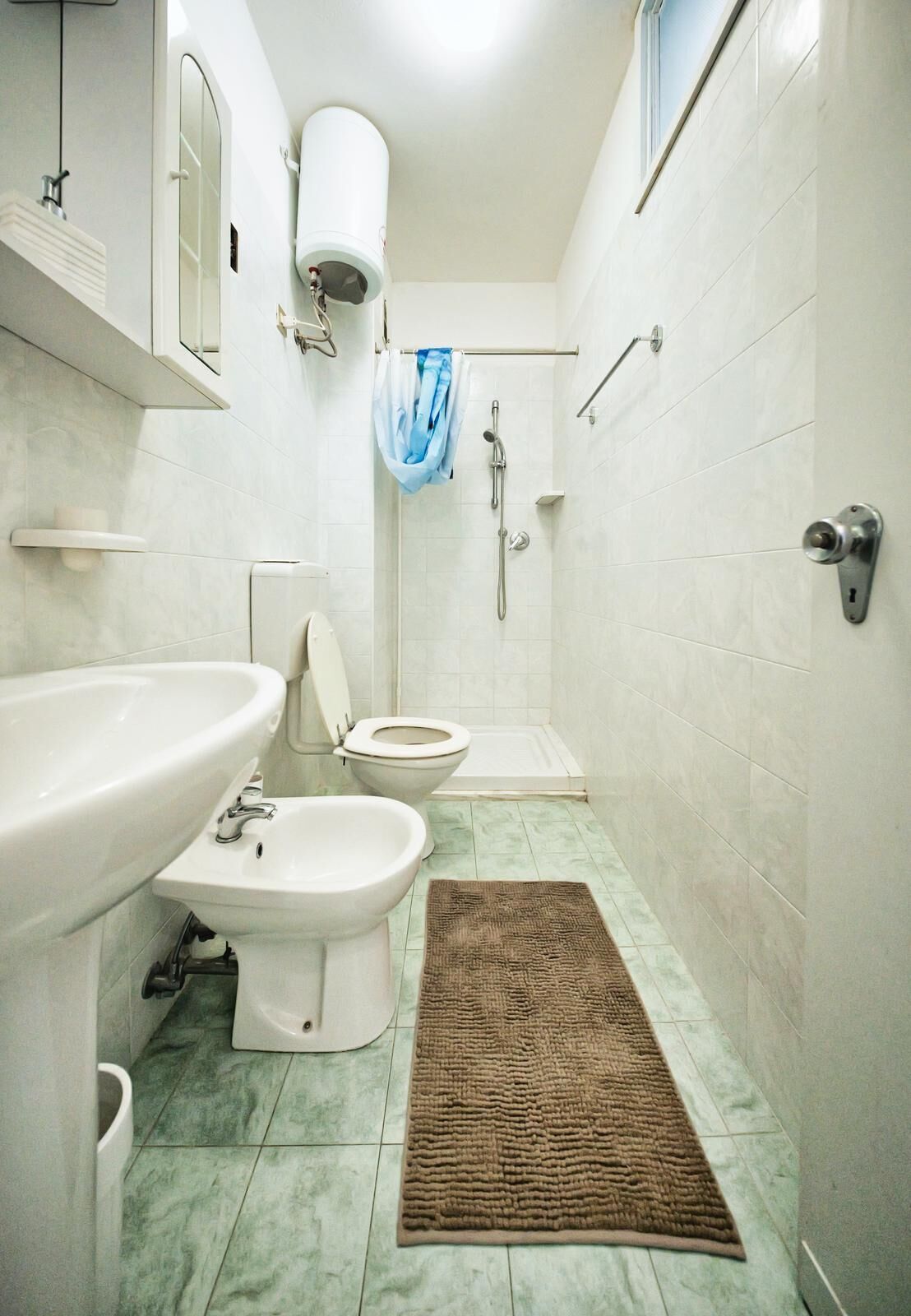 A bathroom with a sink, bidet, toilet, shower, and a towel rack.
