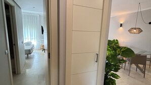 A hallway with a white door, a potted plant, and a dining area with a table and chairs. - LAS COLINAS GOLF (Dehesa de Campoamor)