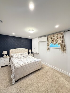A bedroom with a bed, nightstands, a dresser, a window with curtains, and a ceiling light. - The Cozy Inn (Halifax)