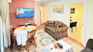 A living room with a dining table, sofa, TV, and artwork. - The Cozy Inn (Halifax)
