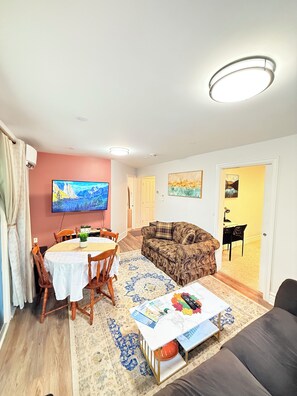 A living room with a dining table, sofa, TV, and artwork. - The Cozy Inn (Halifax)