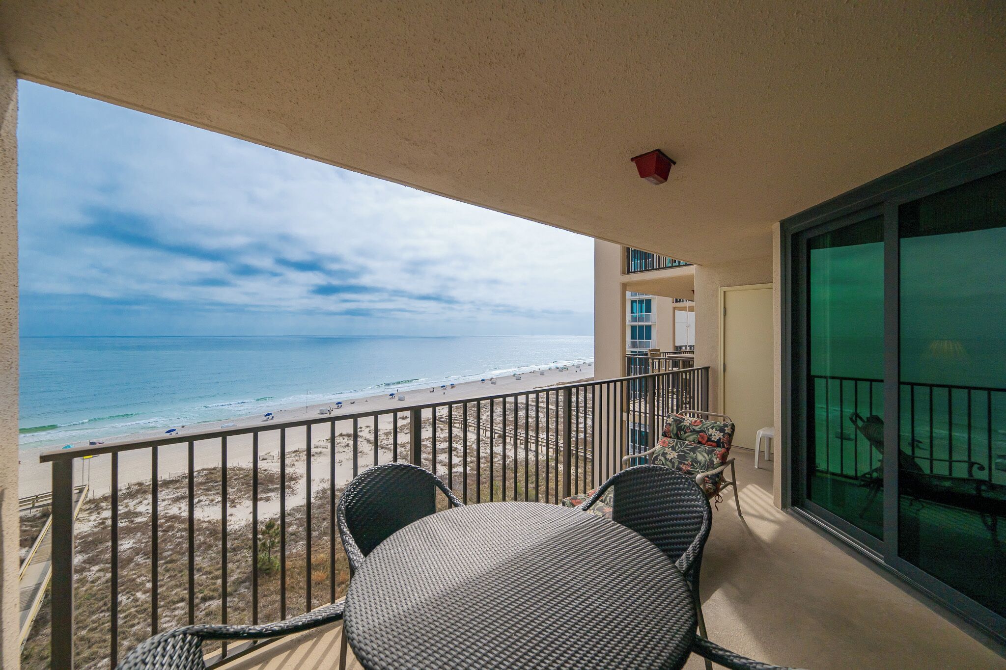 Un balcon avec vue sur la plage, une table et des chaises.