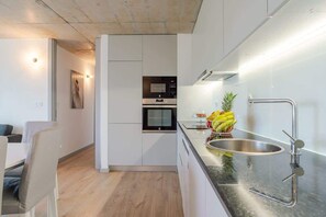 Eine moderne Küche mit Backofen, Spüle aus Edelstahl und Obstschale auf der Arbeitsfläche.