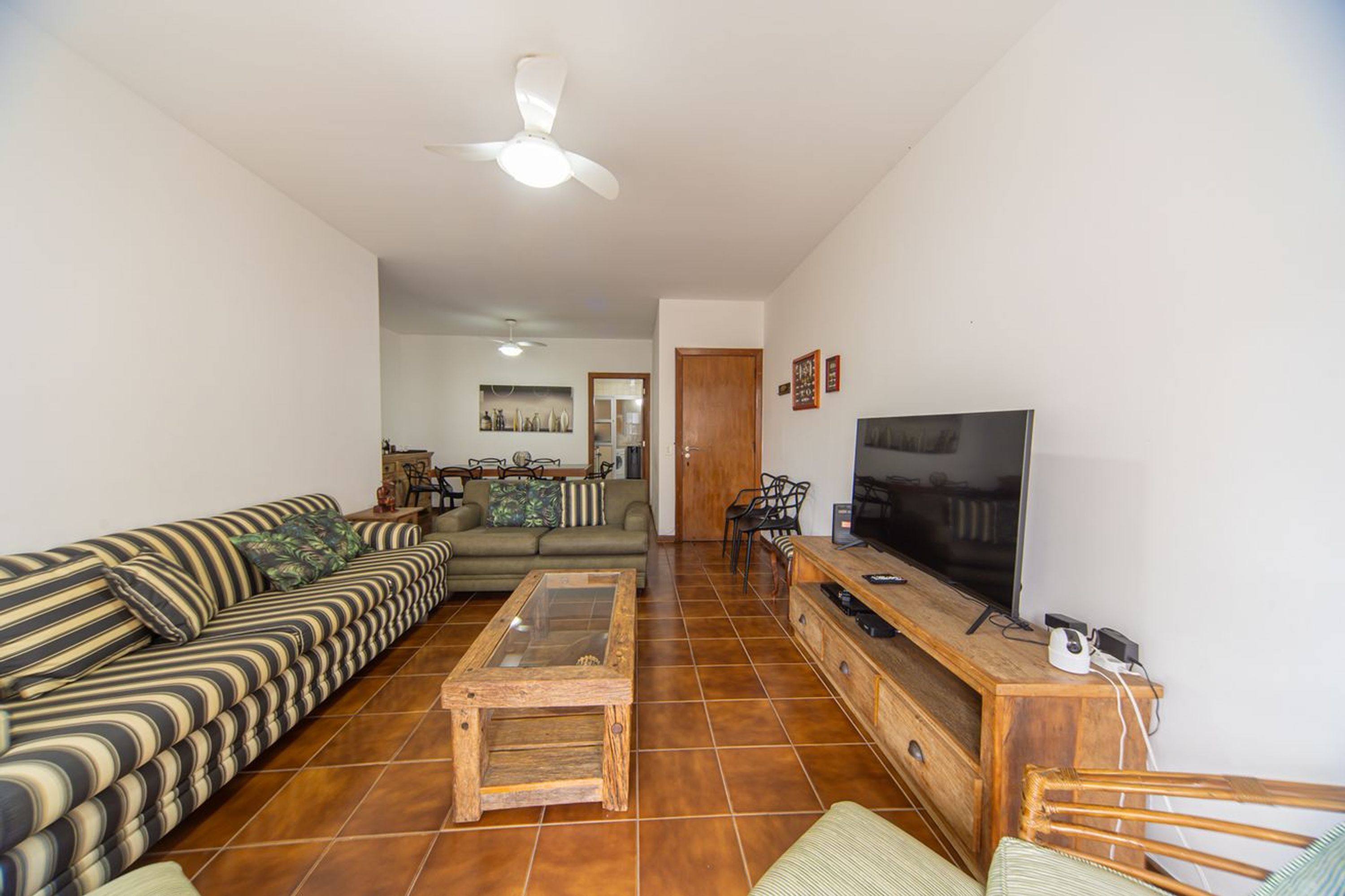 Una sala de estar con sofá, mesa de centro, televisor y ventilador de techo.