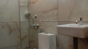 Um banheiro com vaso sanitário, chuveiro e pia.